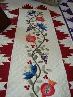 a quilted table runner with flowers and leaves on it