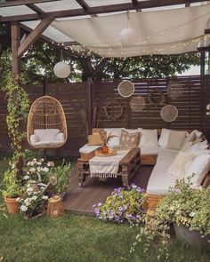 an outdoor living area with white furniture and string lights hanging from the pergolated roof