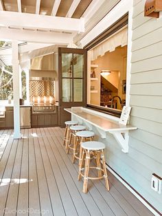 an outdoor kitchen with stools on the front porch