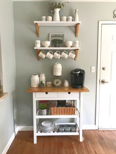 a small kitchen island with shelves on the wall above it and coffee maker in front of it