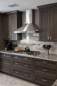 a kitchen with marble counter tops and dark wood cabinets