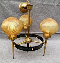 three golden glass lamps sitting on top of a black stand