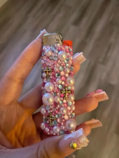 a person holding a cell phone covered in pearls and other things on their fingers,