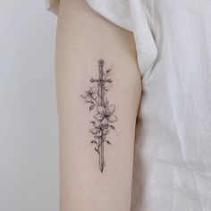 a cross and flowers tattoo on the left upper half of the arm, which is black and white