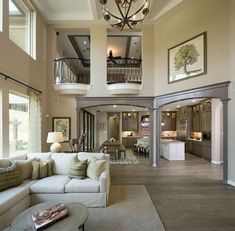 a living room filled with furniture and a chandelier hanging from the top of two story ceilings