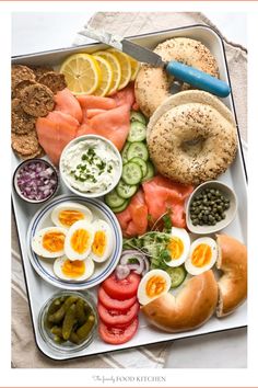 a tray filled with different types of food including bagels, eggs, and pickles