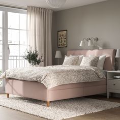 a bedroom with a pink bed and white rugs on the wooden floor next to a large window