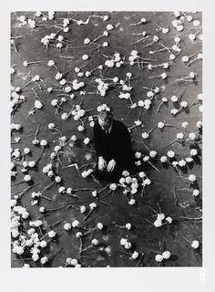 a man sitting on the ground surrounded by flowers in black and white photo taken from above