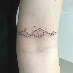 a small mountain tattoo on the left inner arm, with stars in the sky above it