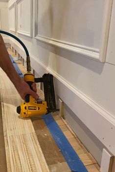 a person using a power drill to attach wood planks in a room with white walls