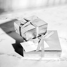 two wrapped presents sitting on top of a marble table next to each other with a price tag