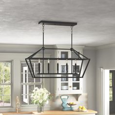 a kitchen with a light fixture hanging from the ceiling and an island in front of it