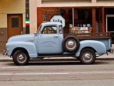 an old blue truck parked in front of a store