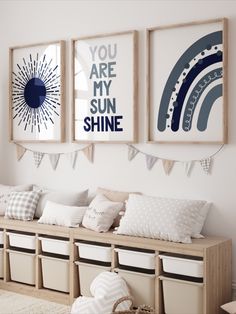 three framed pictures hang on the wall above a bench with storage bins underneath them