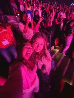 two girls are smiling and posing for the camera in front of an audience at a concert