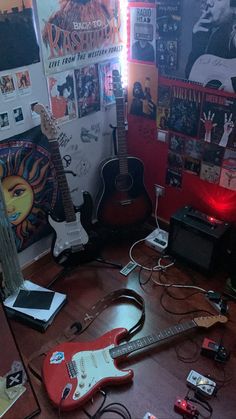 a room with guitars and other musical equipment on the floor in front of a wall full of posters