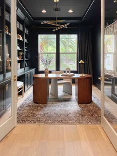 a dining room with black walls and wood flooring is seen through the glass doors