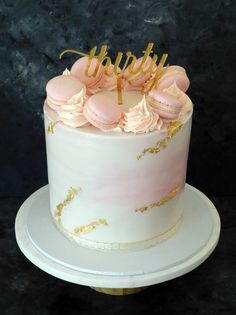 a white cake with pink frosting and gold decorations