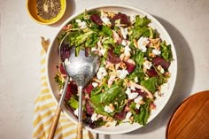 a white bowl filled with salad next to a wooden spoon