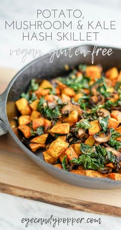 a skillet filled with mushrooms and kale on top of a wooden cutting board