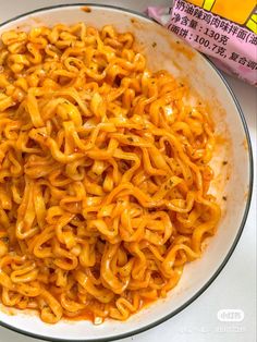 a bowl filled with noodles and sauce next to a bag of macaroni and cheese