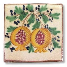 two pomegranates with green leaves and berries on a white tile background