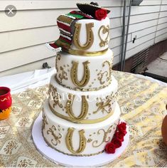 a three tiered wedding cake with red roses on the bottom and gold decorations around it