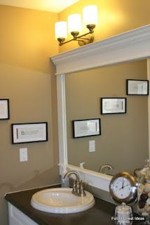 a bathroom sink sitting under a mirror next to a wall mounted clock and framed pictures