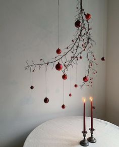 two candles are sitting on a table with ornaments hanging from it