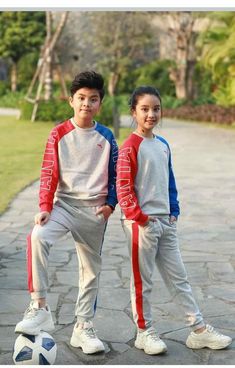 two young children standing next to each other with soccer balls on the ground in front of them