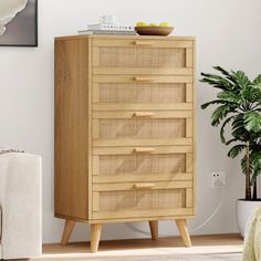 a wooden cabinet with wicker drawers next to a couch and potted plant in the corner