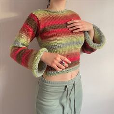 a woman with her hands on her hips wearing a colorful knitted sweater and skirt