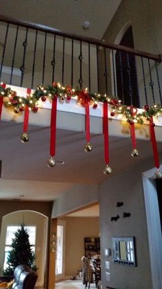 christmas decorations are hanging from the banisters in this living room with red ribbon