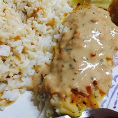 a plate with rice, meat and gravy on it next to a fork