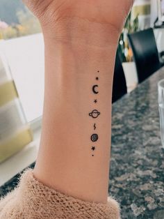 a woman's wrist tattoo with the planets and stars on her left arm,