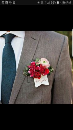 a man wearing a suit and tie with flowers on the lapel, holding a name tag