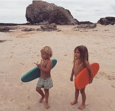 two young children holding surfboards on the beach