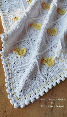 a crocheted blanket with rubber ducks on the front and bottom, sitting on a wooden floor