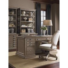 an office desk with a chair and bookcase in front of the window, next to a lamp