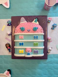 a cake shaped like a house on top of a table next to other toys and decorations