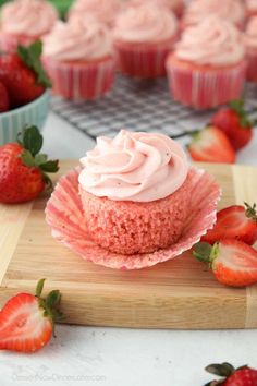 strawberry cupcakes with frosting and strawberries in the background