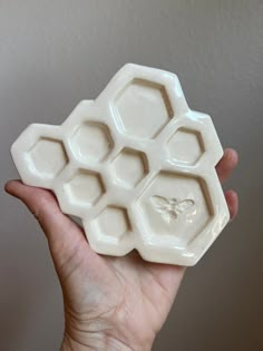 a hand holding an ice tray with honeycombs on the top and bee in the middle