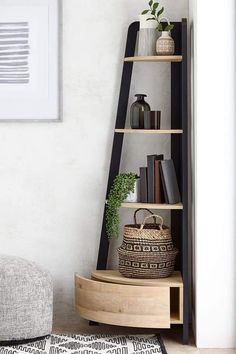 a wooden shelf with books and baskets on it next to a wall mounted art piece