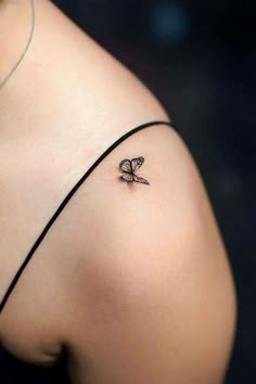 a woman's shoulder with a small butterfly tattoo on the left side of her arm