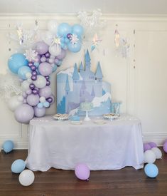 a table topped with balloons and cake next to a castle