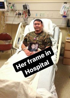 a man sitting in a hospital bed holding a framed photo with the caption her frame in hospital