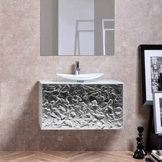 a bathroom sink sitting under a mirror next to a wall mounted faucet and framed pictures