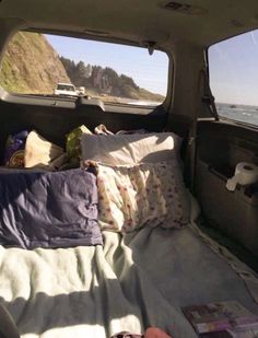 there is a bed in the back of a truck with pillows and blankets on it