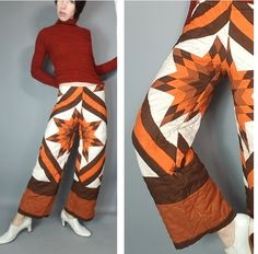 an orange and brown patterned pants with white shoes next to a mannequin's torso