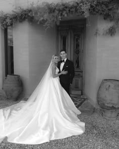 a bride and groom pose in front of an old building